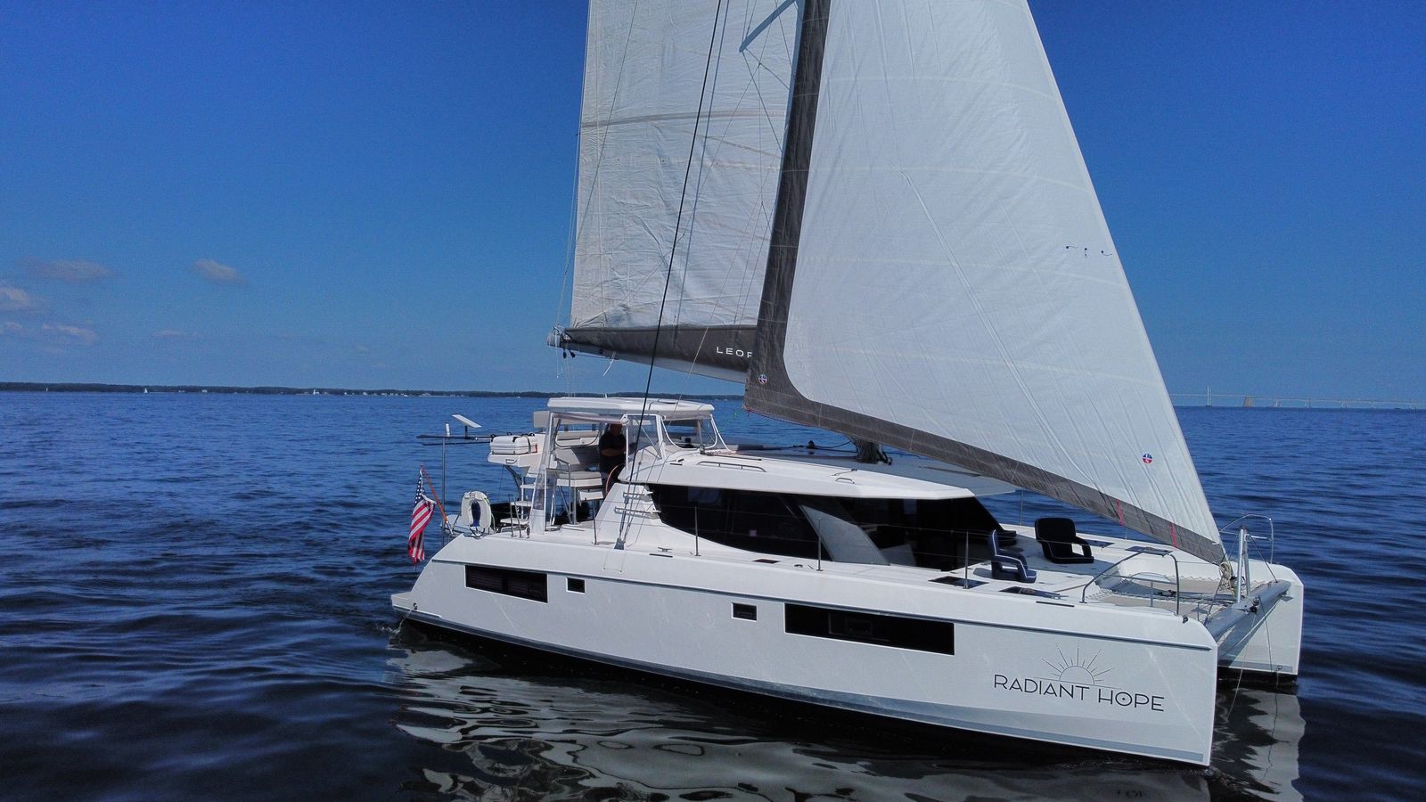 Broadside sails-up view with Bay Bridge context
