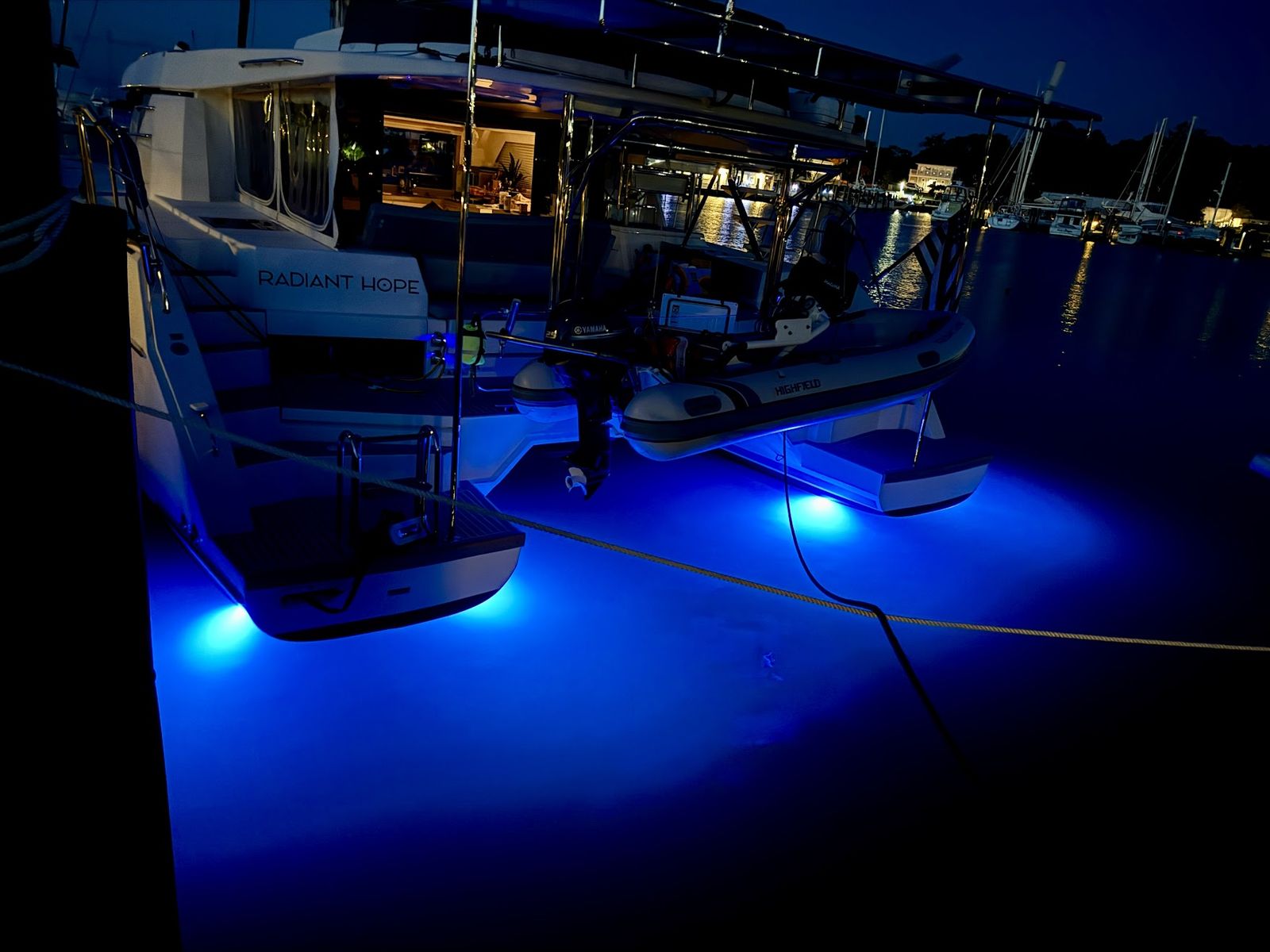 Night stern with Highfield tender, underwater lights, and Radiant Hope lettering